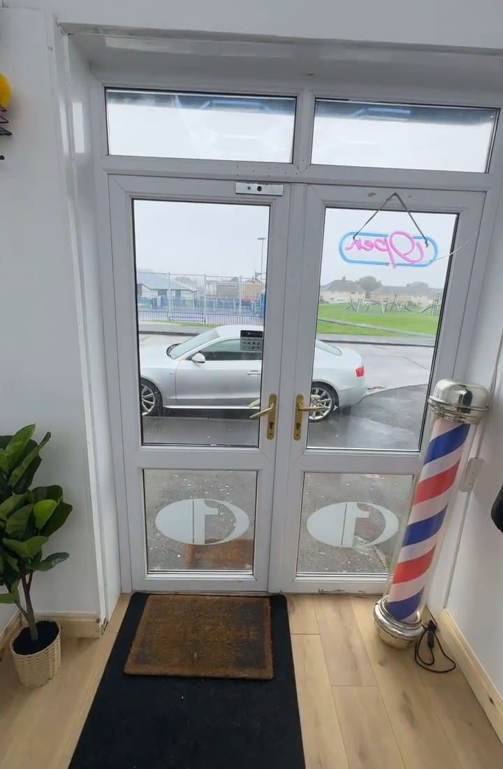 The front door at Zizo Barbers with the barber pole and Open sign